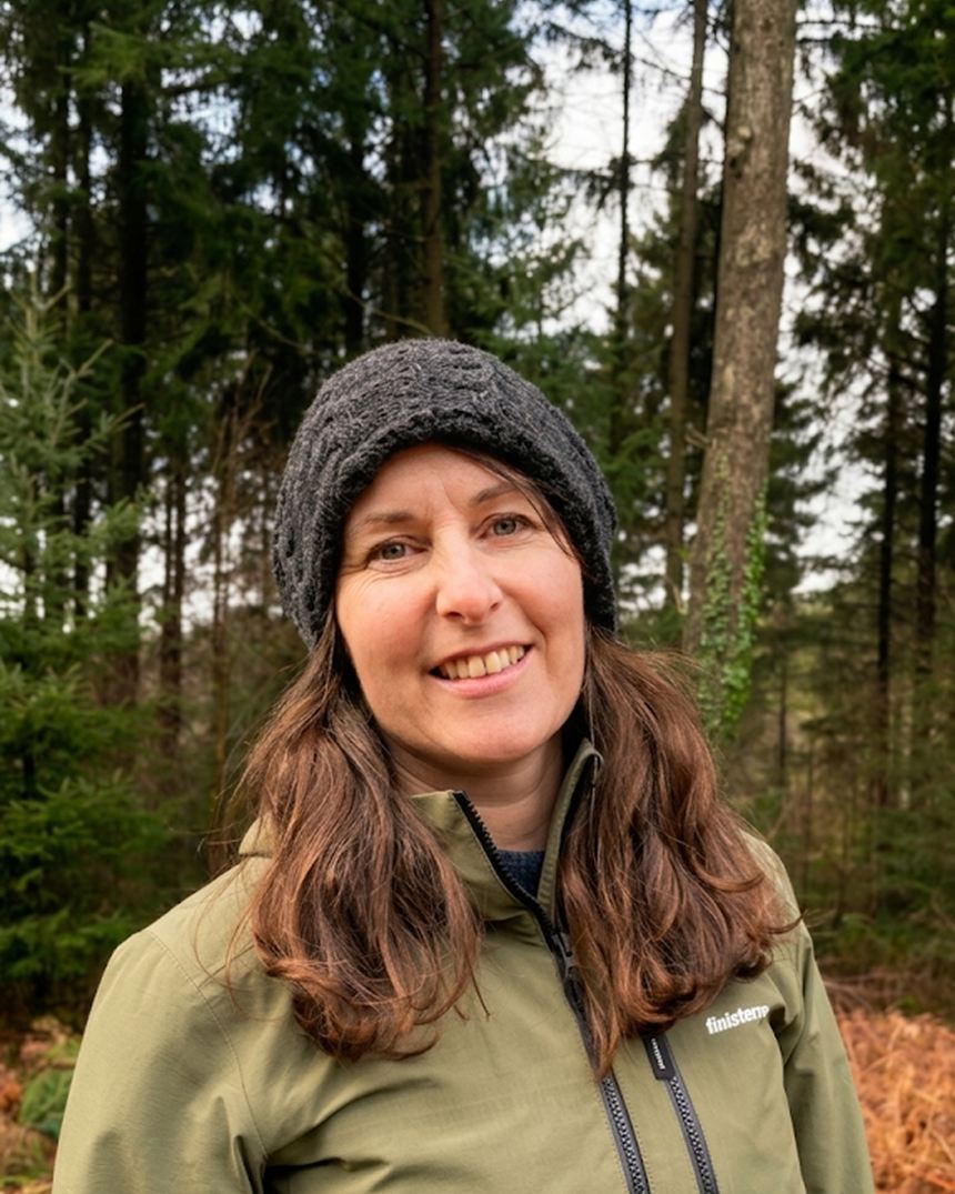 Anna in winter woodland, wrapped up against the cold, bare trees behind her.